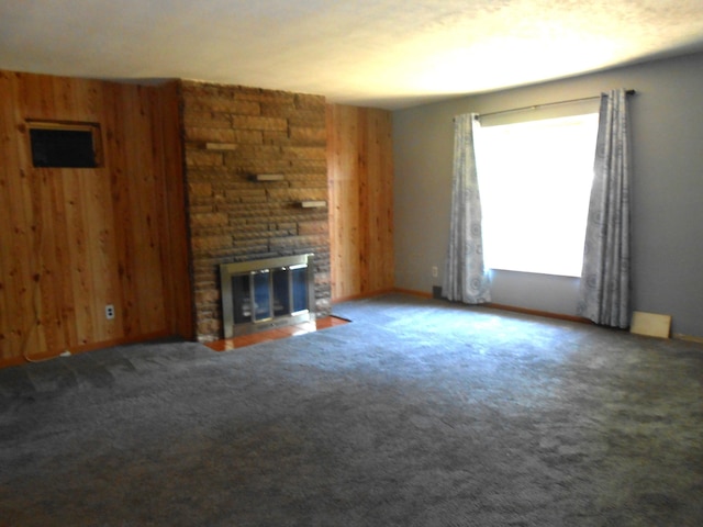 unfurnished living room featuring wood walls, carpet floors, and a fireplace