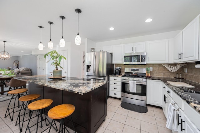 kitchen featuring tasteful backsplash, stainless steel appliances, a center island, white cabinetry, and a breakfast bar area