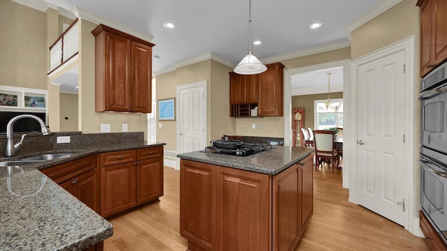 kitchen with a kitchen island, light hardwood / wood-style flooring, dark stone countertops, and sink