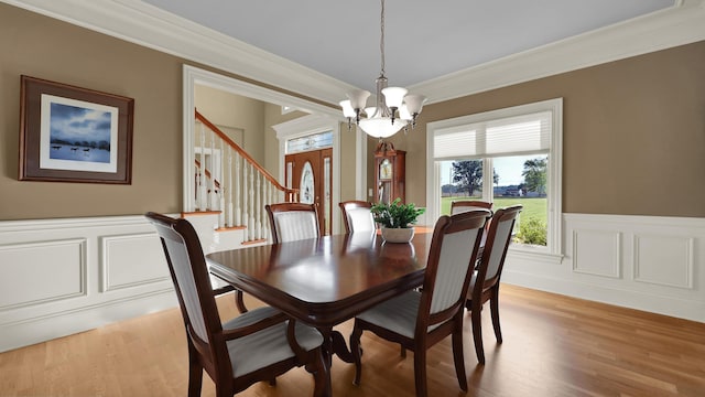 dining room with light wood-type flooring, ornamental molding, and an inviting chandelier