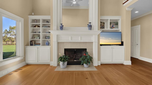 unfurnished living room featuring crown molding, a fireplace, ceiling fan, and light wood-type flooring