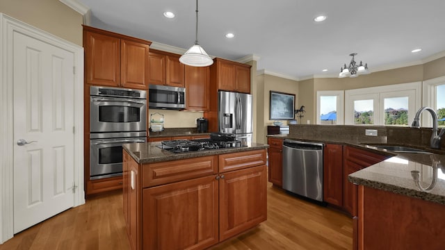 kitchen featuring light hardwood / wood-style floors, a center island, hanging light fixtures, and appliances with stainless steel finishes