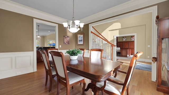 dining room featuring crown molding, light hardwood / wood-style floors, and an inviting chandelier