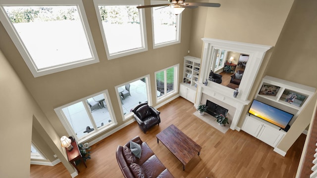 living room featuring ceiling fan, a towering ceiling, and hardwood / wood-style flooring