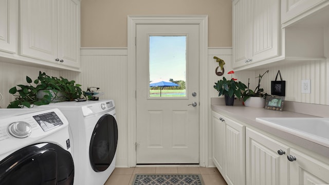 washroom with washing machine and clothes dryer, light tile patterned floors, and cabinets