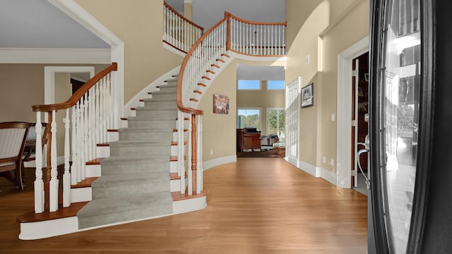 entryway featuring a towering ceiling, hardwood / wood-style flooring, and ornamental molding