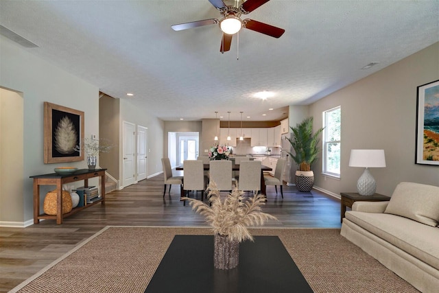 living room with ceiling fan, dark hardwood / wood-style flooring, and a textured ceiling