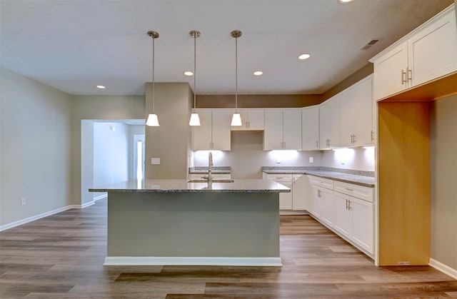 kitchen with sink, light hardwood / wood-style flooring, white cabinetry, and an island with sink