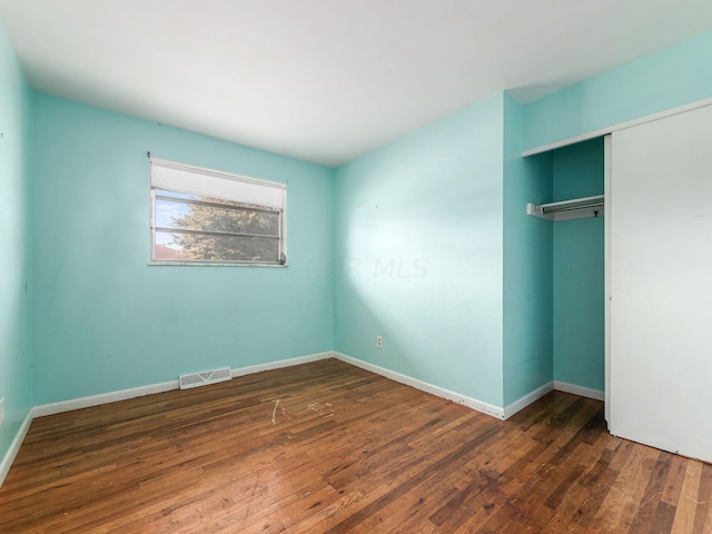 unfurnished bedroom featuring dark hardwood / wood-style floors and a closet