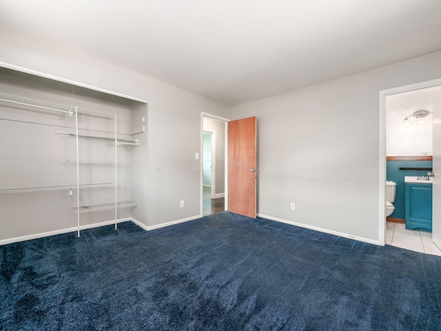 unfurnished bedroom featuring ensuite bath, light carpet, and a closet