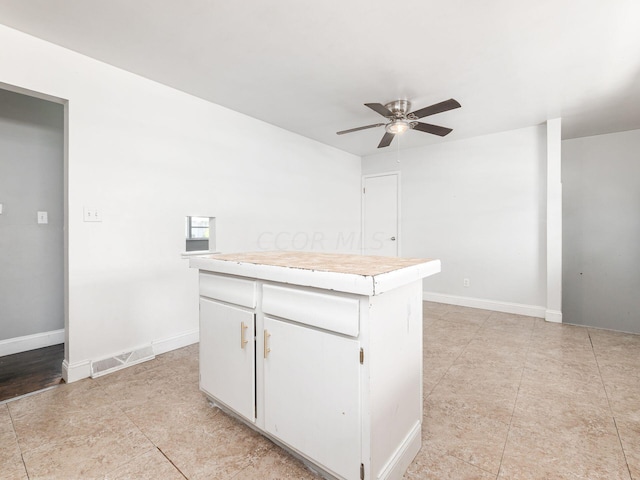 kitchen with white cabinets, a kitchen island, and ceiling fan