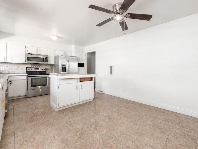 kitchen featuring backsplash, white cabinets, a kitchen island, and appliances with stainless steel finishes