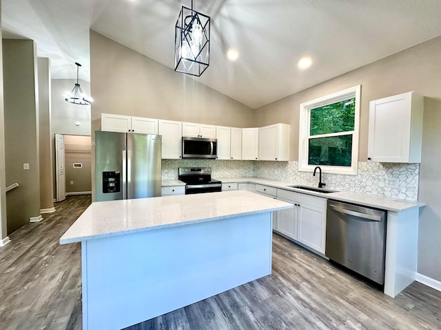 kitchen with white cabinetry, sink, pendant lighting, a kitchen island, and appliances with stainless steel finishes