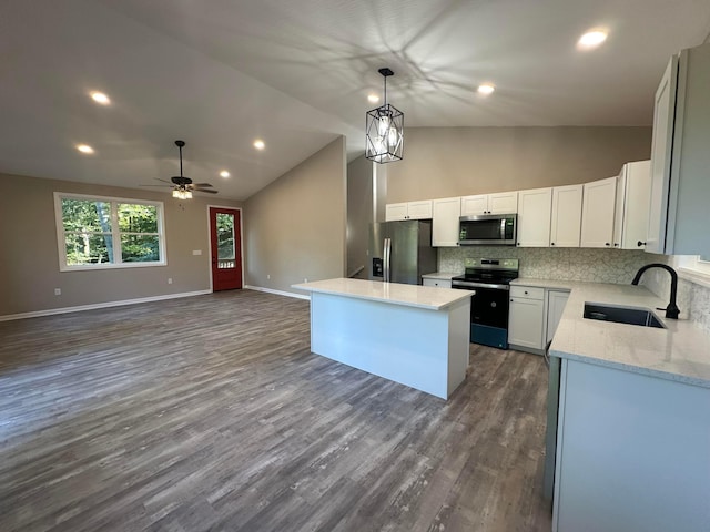 kitchen with sink, vaulted ceiling, appliances with stainless steel finishes, a kitchen island, and white cabinetry