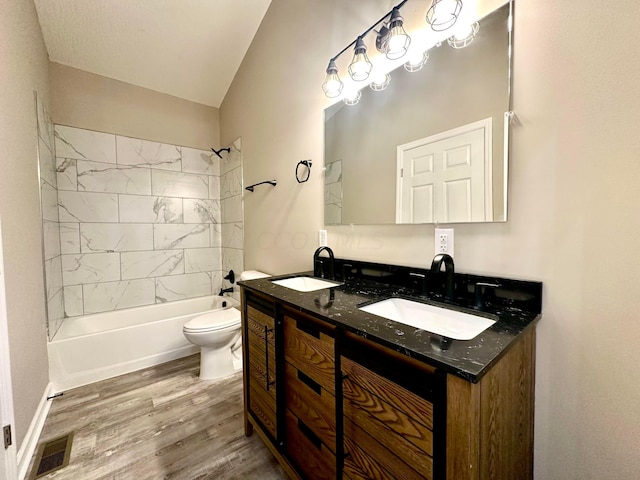 full bathroom featuring vanity, vaulted ceiling, tiled shower / bath combo, toilet, and wood-type flooring