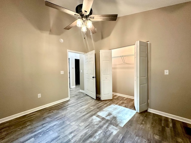 unfurnished bedroom with dark hardwood / wood-style flooring, ceiling fan, a closet, and a high ceiling