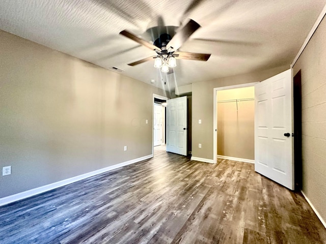 unfurnished bedroom with a closet, ceiling fan, dark hardwood / wood-style flooring, and a textured ceiling