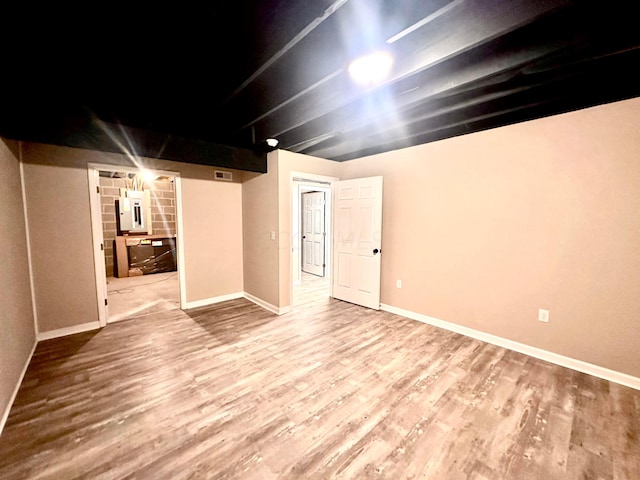 basement featuring electric panel and wood-type flooring