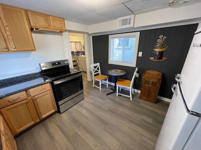 kitchen featuring dark stone countertops, electric range, and hardwood / wood-style floors