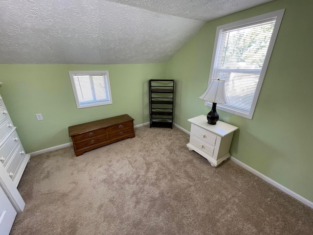 unfurnished bedroom with a textured ceiling, light colored carpet, and vaulted ceiling