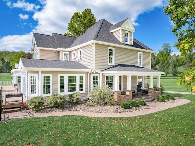 rear view of house with a porch and a yard