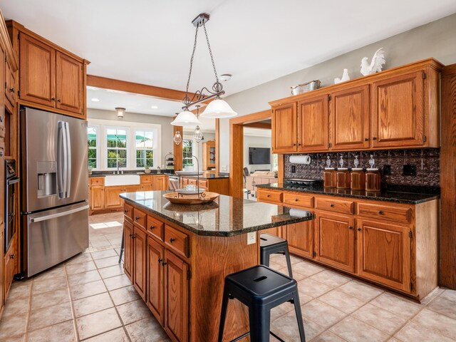 kitchen featuring decorative backsplash, stainless steel refrigerator with ice dispenser, a kitchen breakfast bar, decorative light fixtures, and a center island