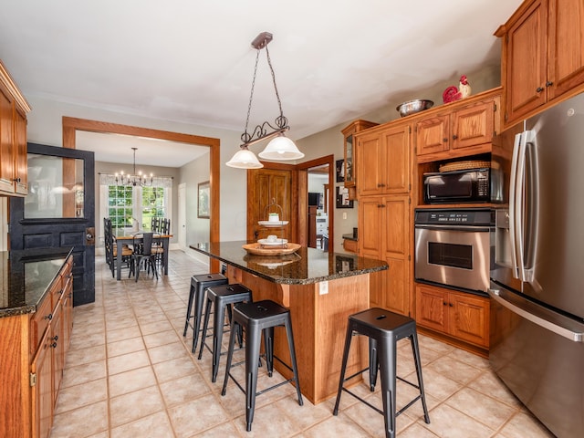 kitchen with dark stone counters, a center island, appliances with stainless steel finishes, and a chandelier