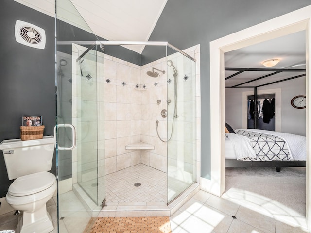 bathroom featuring tile patterned flooring, a shower with door, and toilet