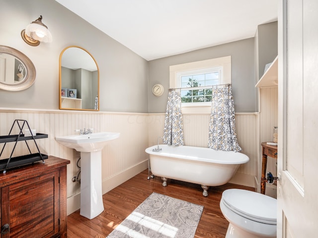 bathroom with sink, a washtub, wood-type flooring, and toilet