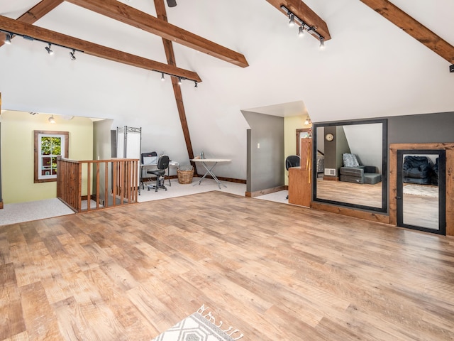 living room featuring rail lighting, beamed ceiling, high vaulted ceiling, and light hardwood / wood-style flooring