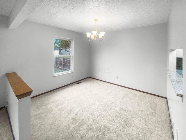 empty room featuring carpet, a chandelier, and a textured ceiling