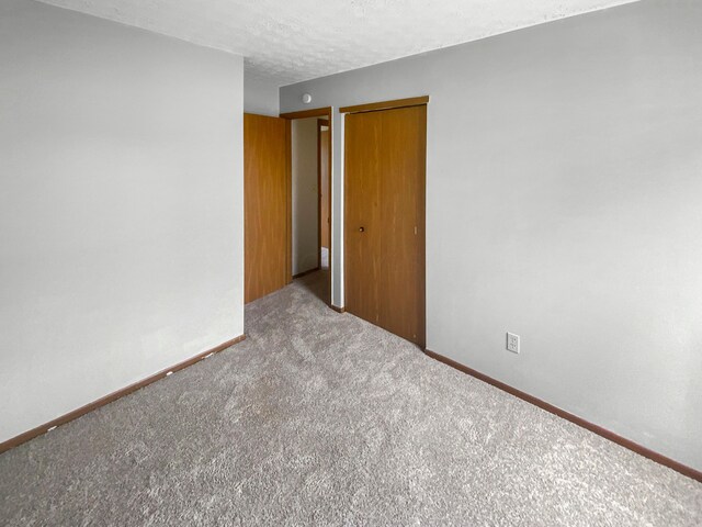 carpeted empty room with a textured ceiling