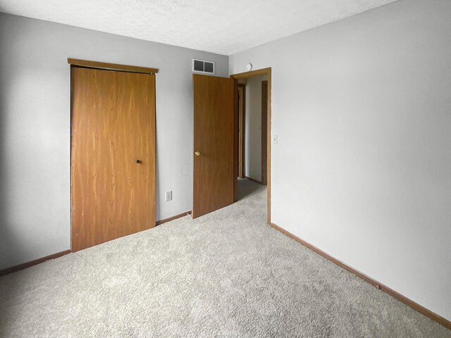 unfurnished bedroom featuring a closet, carpet, and a textured ceiling