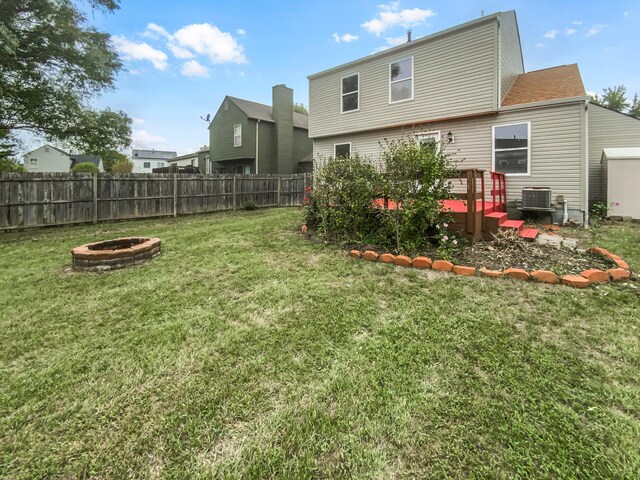 rear view of house featuring a yard, central AC, a fire pit, and a deck