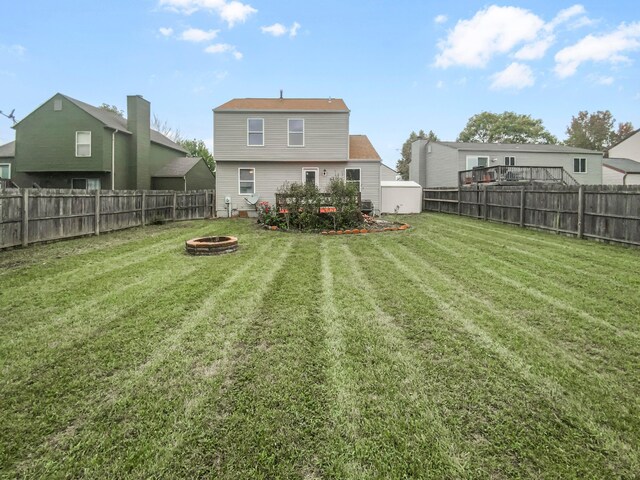 rear view of house with a yard and an outdoor fire pit