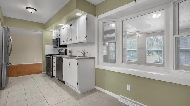 kitchen featuring white cabinetry, sink, light tile patterned floors, and stainless steel appliances