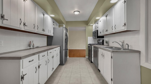 kitchen featuring stainless steel appliances, sink, light tile patterned floors, and white cabinets