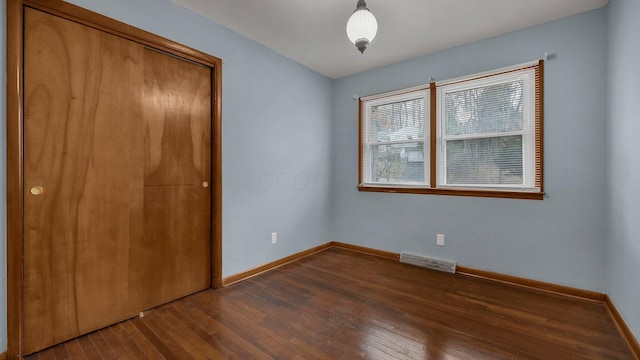 unfurnished bedroom with dark hardwood / wood-style flooring and a closet