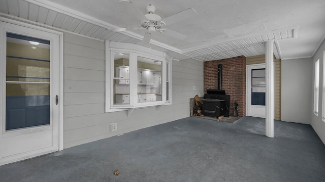 unfurnished living room featuring ceiling fan and a wood stove