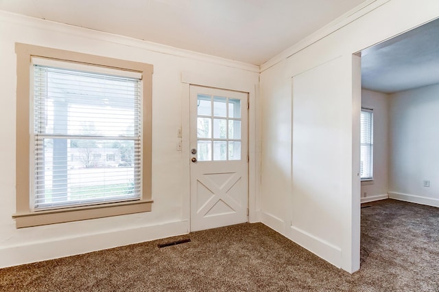 doorway to outside with dark colored carpet and crown molding