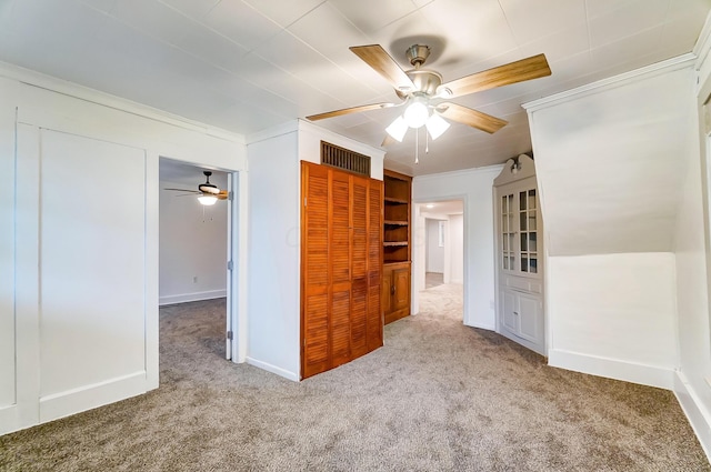 empty room with ceiling fan, ornamental molding, and carpet