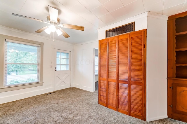 unfurnished bedroom with a closet, ornamental molding, ceiling fan, and light carpet