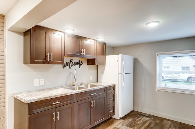 kitchen featuring light stone counters, white fridge, dark hardwood / wood-style floors, and sink