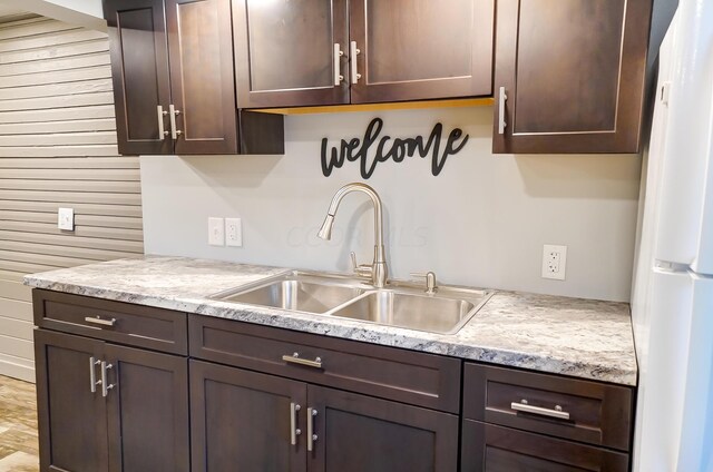 kitchen featuring sink, white fridge, and dark brown cabinetry