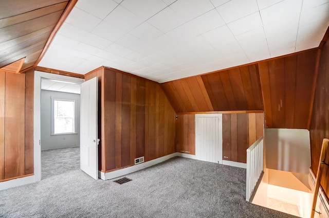 bonus room with lofted ceiling, carpet, and wood walls