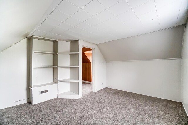 additional living space with vaulted ceiling, carpet floors, and built in shelves