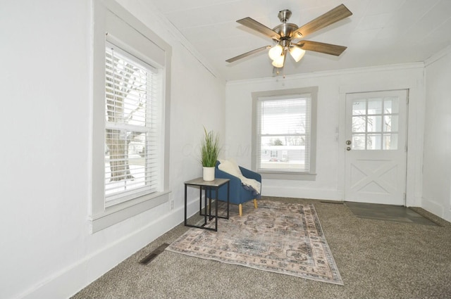 interior space featuring ceiling fan, carpet, ornamental molding, and a wealth of natural light