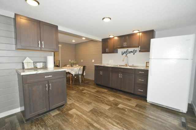 kitchen with sink, dark wood-type flooring, white fridge, and dark brown cabinets