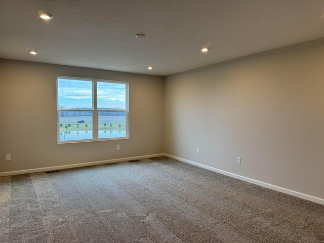 carpeted spare room with a water view