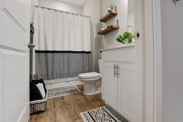 bathroom with hardwood / wood-style floors, vanity, toilet, and walk in shower